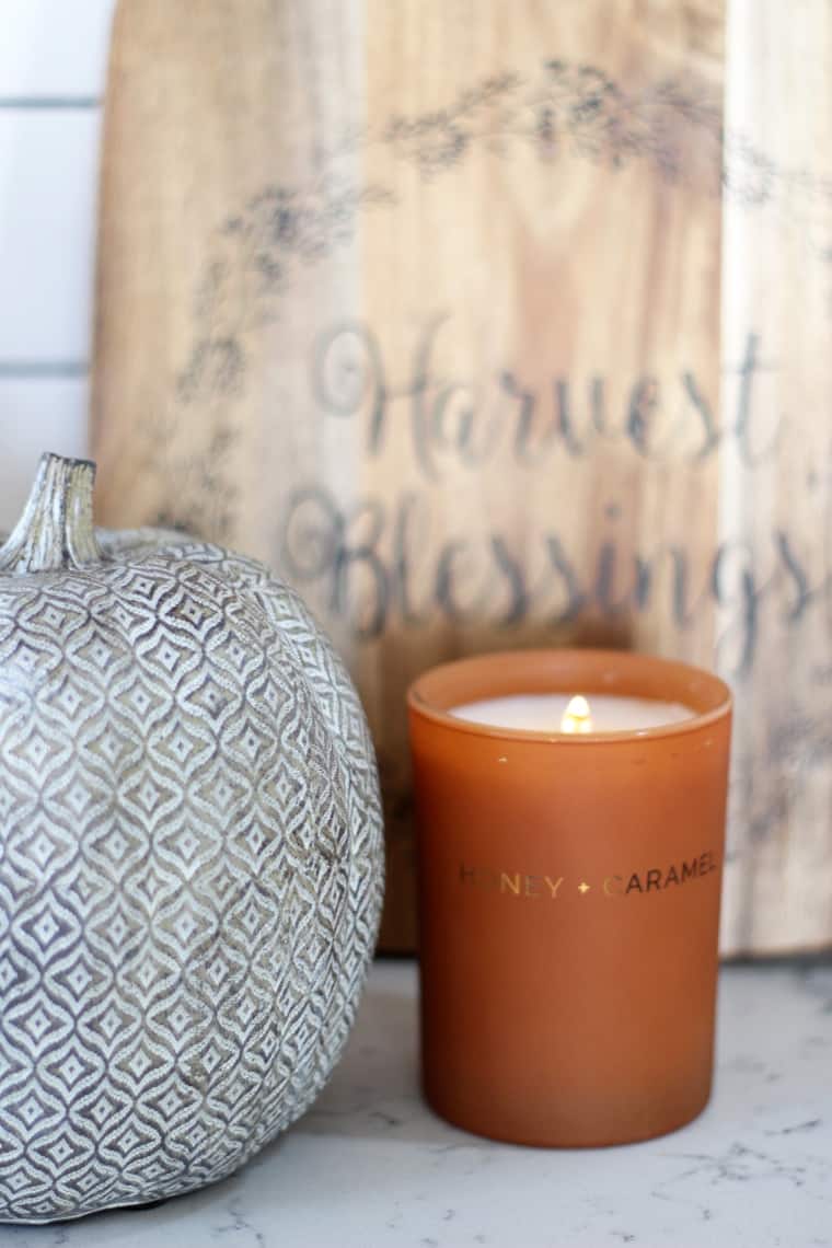 Detailed vignette with a wooden cutting board, caramel candle and patterned decorative pumpkin.